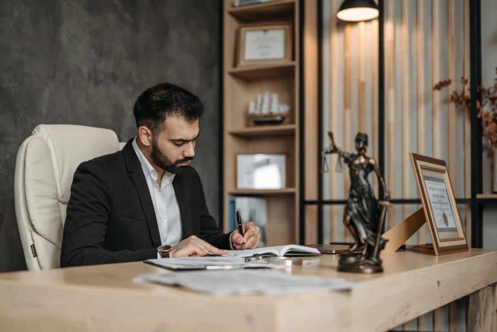 A focused lawyer in an office setting writing and reviewing legal documents, symbolizing expertise and professionalism.